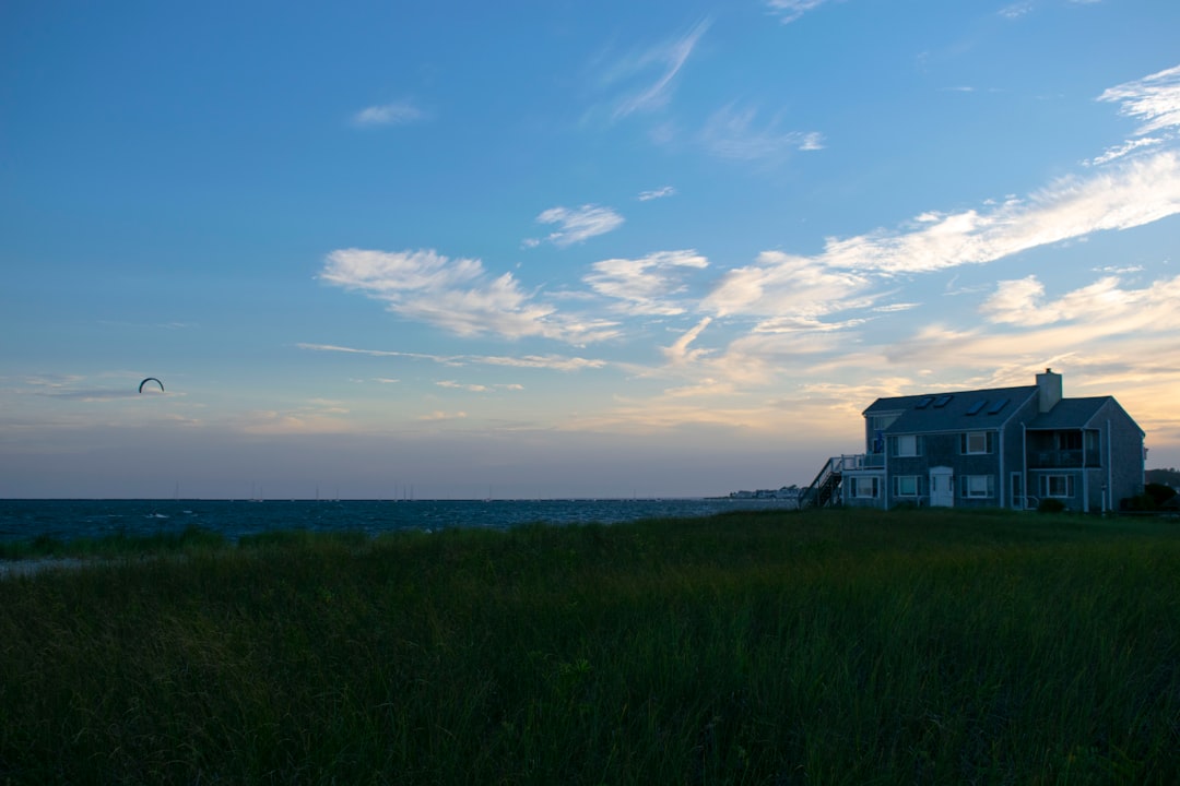 A strong, well-built beach house stands intact under a dramatic sky as dark storm clouds part, symbolizing resilience and the peace of mind that comes with a storm-proof home.