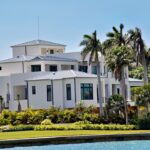 Well-maintained Gulf Coast home stands securely next to a dock where a charter fishing boat is moored on a bright, sunny d...