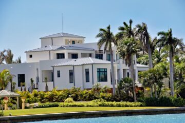 Well-maintained Gulf Coast home stands securely next to a dock where a charter fishing boat is moored on a bright, sunny d...