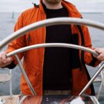 Confident, professional fishing guide at the helm of his charter boat, navigating through the water on a bright, sunny day...