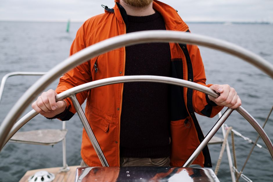 Confident, professional fishing guide at the helm of his charter boat, navigating through the water on a bright, sunny day...